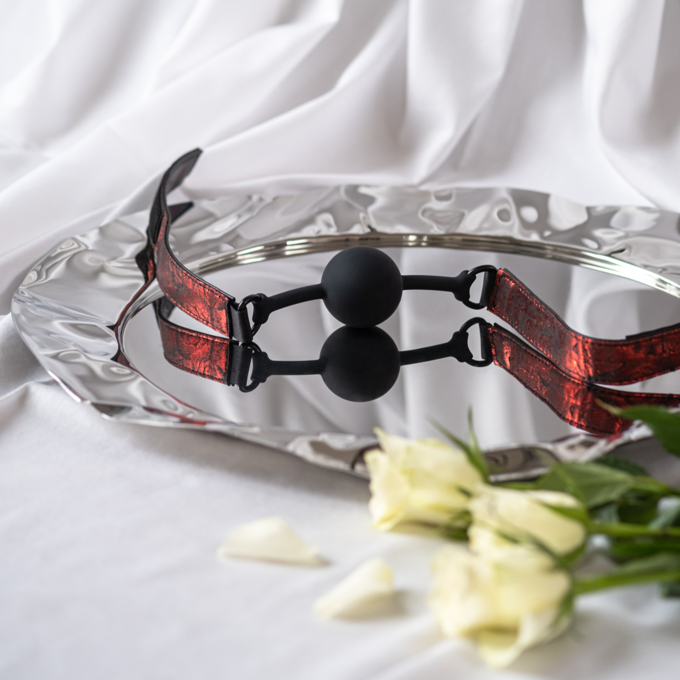 The Sweet Anticipation ball gag by Fifty Shades of Grey sits on a silver platter with flowers.